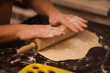 cook rolls out the dough, men's hands work with the dough, cooking dough for dumplings, cook's hands in flour