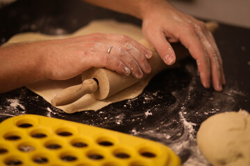 cook rolls out the dough, men's hands work with the dough, cooking dough for dumplings, cook's...