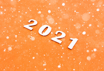 Close-up of wooden numbers 2021 on orange background with stars. New years content.