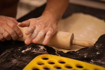 cook rolls out the dough, men's hands work with the dough, cooking dough for dumplings, cook's...