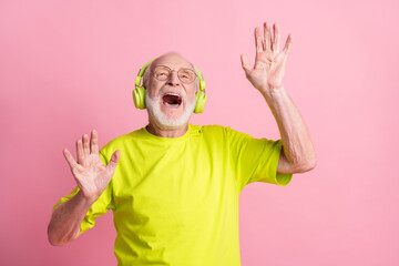Photo of crazy old man listen music dance arms wear headphones spectacles lime color clothes isolated on pink background
