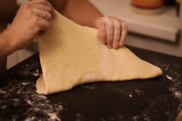 cook rolls out the dough, men's hands work with the dough, cooking dough for dumplings, cook's...