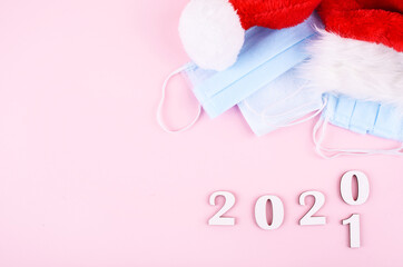 Medical protective mask on a pink background.Santas cup. New Year and coronavirus concept.The inscription of a HEALTHY NEW YEAR.