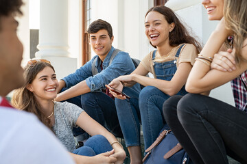 Teenager friends sitting together and laughing - obrazy, fototapety, plakaty