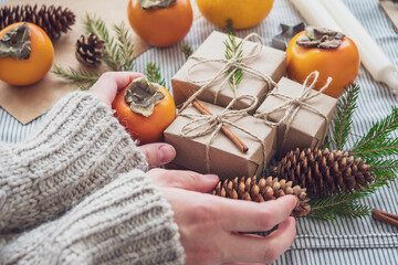 The girl makes a new year composition of gifts Packed with her own hands in Kraft paper, top view, close-up. Happy Christmas background. Preparing for the holiday. Xmas concept
