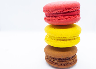 Macaroni, red, yellow and brown, are stacked one on top of the other in the form of a tower on a white background.