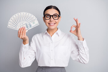 Photo of funky girl hold fan cash show okey beaming smile wear spectacles white shirt isolated grey color background