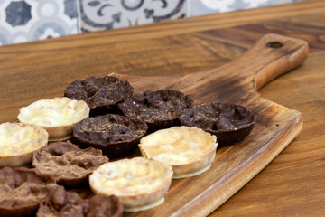 Chocolate coated hazelnut and rice florentines on wood chopping board.  White, milk and dark chocolate selection