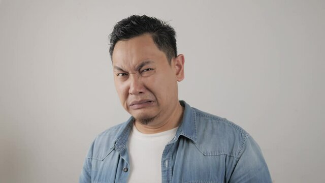 Photo image of crying sad young Asian man showing surrender gesture, hands raised up asking to stop bully on him