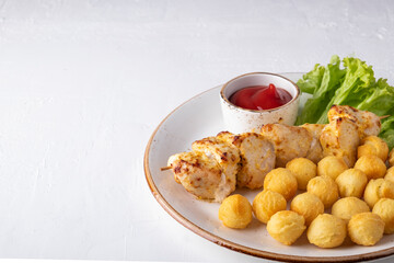 Baked chicken pieces on a wooden skewer with potato balls