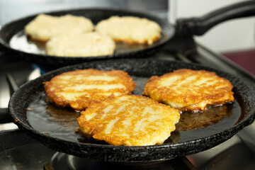 Potato pancakes frying on a pan.