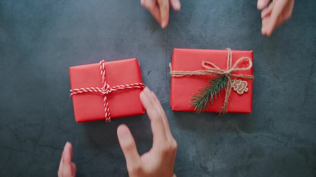 Hands of people putting craft paper gift box on concrete background and copy space. for present Christmas and new year holiday.
