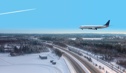 Fototapeta na wymiar A passenger plane landing at Oslo Gardermoen International Airport - Airport in a snow covered - Beautiful winter landscape with aerial view of highway road and snow-covered road