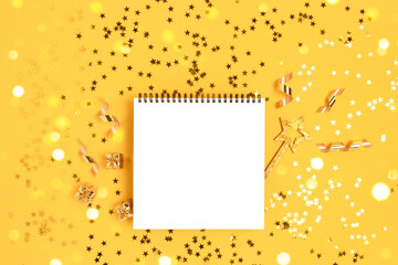 Notepad mockup with magic wand and gift boxes on a yellow glittering background. Golden shiny confetti.