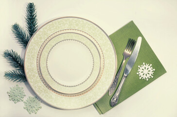 Table setting. Plate, fork, knife and green  napkin on the table. New Year's festive table setting.
