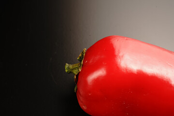 Part of a red hot pepper on a black background. Bright color.