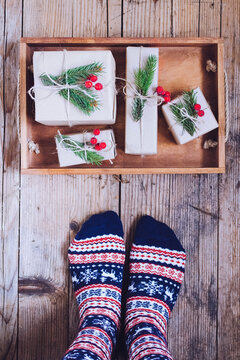 Feet With Warm Winter Socks Standing In Front Of Christmas Gifts