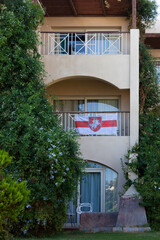 Fototapeta na wymiar flag of belarus with the coat of arms on the balcony in Egypt. Patriotism. Beautiful building with green plants