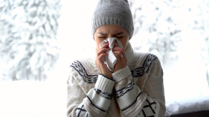 Morbid woman using a tissue outdoor in winter scenery
