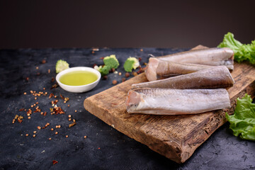 Fresh fish notation on a wooden board, with olive oil, sauce, spices, fresh lettuce leaves. Useful food.