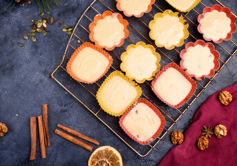 Preparation of raw dough for vanilla muffins in moulds of different shapes. Nuts, cinnamon sticks, raisins, sprigs ate. New Year's treats.