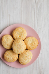 Homemade Flaky Buttermilk Biscuits on a pink plate on a white wooden surface, top view. Flat lay, overhead, from above. Copy space.