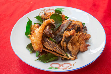 Lao Homemade Fried Fish on plate with Kaffir lime leaves, Top view