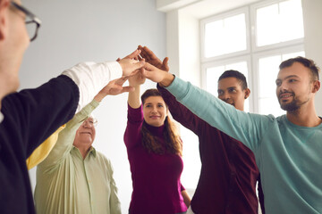 Team of happy diverse people joining hands during team building activity or club meeting