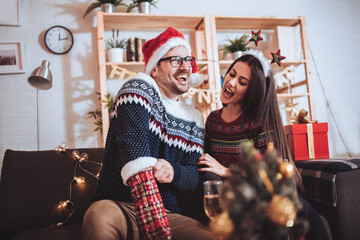 Young couple celebrating Christmas at home opens gift