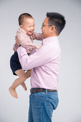 Asian dad hold his toddler son on his chest