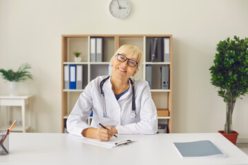 Female family doctor sits in front of the camera and gives an online consultation to her patient.