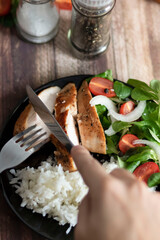 Ready chicken breast with rice and salad. All food on a black plate
