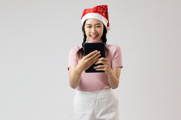 asia young woman in santa claus hat holding tablet on white background
