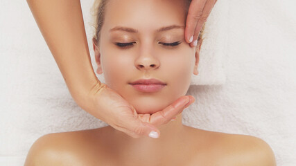 Naklejka premium Young, beautiful and healthy woman in massaging salon. Traditional face massage therapy and skin care.