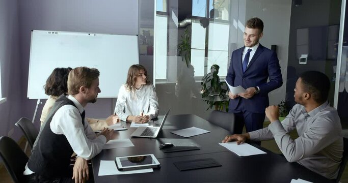 Business team professional managers sitting in office conference meeting listening to leader report discussing successful project analyzing costs conducting brainstorm. Caucasian man giving briefing