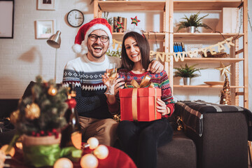 Obraz na płótnie Canvas Young couple celebrating Christmas at home opens gift