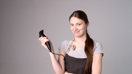 Naklejka premium Young beautiful female hairdresser holding hair clipper