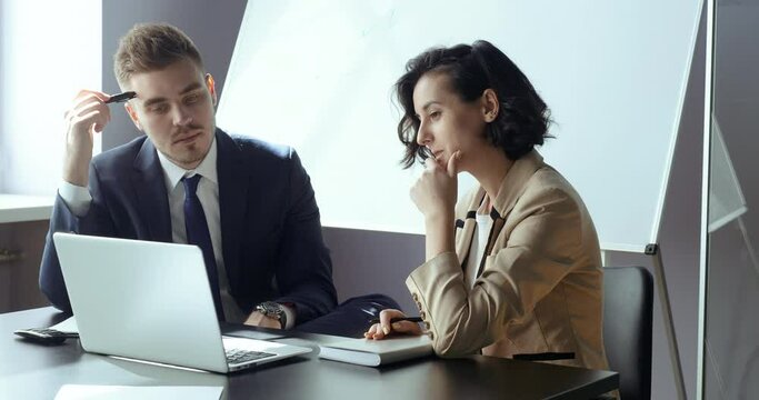 Female professional mentor helping male colleague teach intern training new worker consult customer explain online business services look at laptop screen. Two people discussing case in modern office