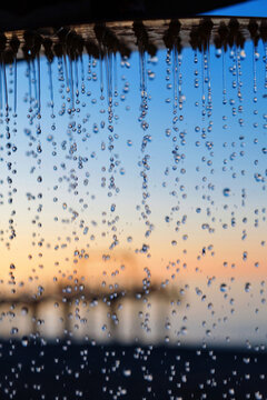 Water pouring from the outdoor beach shower head on blurred sunset seascape background, selective focus © Luka