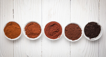 Five types of cocoa in cups on a wooden table
