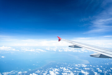 Airplane wing against beautiful tiny cloud and blue sky background.