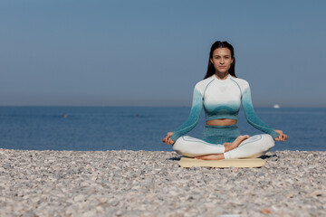 Fototapeta na wymiar Caucasian young woman practicing yoga at seashore