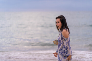 Fototapeta na wymiar young asian woman standing at seashore at dusk.
