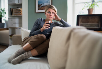 Fototapeta premium Depressed woman with wine indoors at home, mental health and alcohol addiction concept.