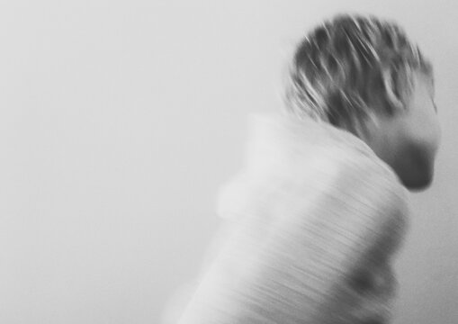 Blurred Motion Of Boy Running Against White Background