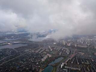 High aerial flight in the clouds over Kiev. An autumn cloudy morning, the Dnieper River is visible on the horizon.