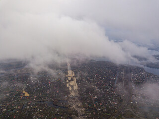 High aerial flight in the clouds over Kiev. An autumn cloudy morning, the Dnieper River is visible on the horizon.