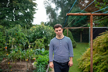 Down syndrome adult man walking outdoors in vegetable garden.