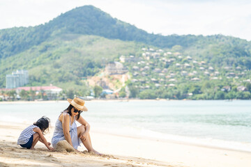 Fototapeta premium Young mother and daughter playing at the sea shore