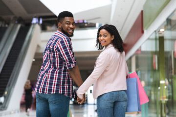 Couple's Leisure. Black Man And Woman Walking In Shopping Mall, Holding Hands